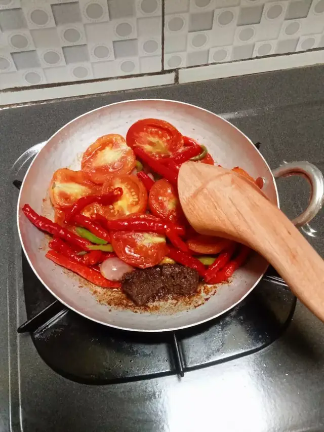 Cabe merah, tomat dan terasi diulek di dalam cobek